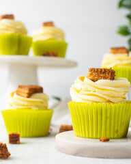 green cupcake with buttercream frosting and a sponge cake garnish on white background, tall buttercream frosting on green cupcakes