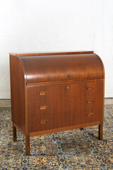Closed roll top writing desk with curved wood top and small drawer handles

