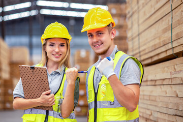 Team engineer carpenter wearing safety uniform and hard hat working holding clipboard checking quality of wooden products at workshop manufacturing. man and woman worker wood warehouse industry.