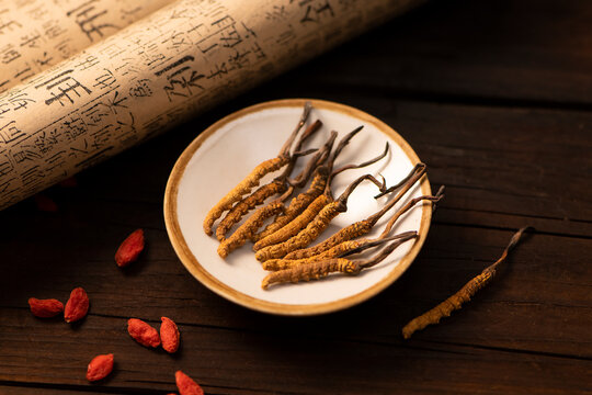 Dried cordyceps sinensis fungus on plate with traditional chinese scroll background