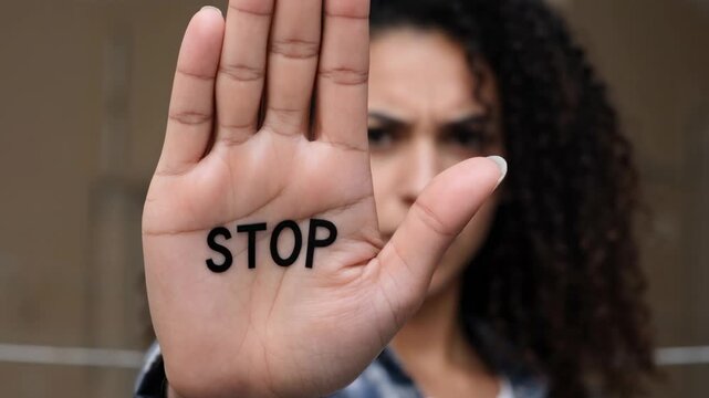Woman Holding Up Hand with &ldquo;STOP&rdquo; Message Forward, conveying strong message of warning, boundaries, and assertive communication.