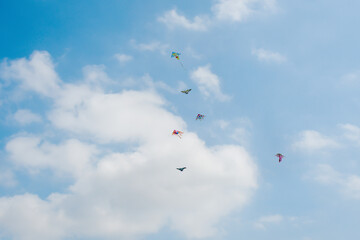 Colorful kites flying high in the blue sky with white clouds