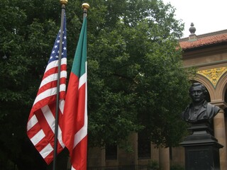 American and italian flags waving together with statue and building