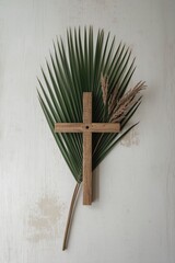 Rustic wooden cross resting on green palm fronds on white background