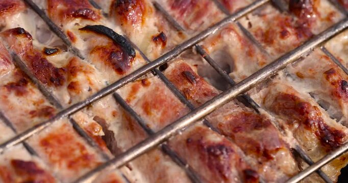 marinated chicken meat with spices during cooking on the grill, fry the chicken fillet on the grill with high heat , close up