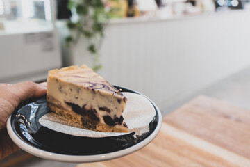 Slice of Plain New York Cheesecake on white plate on wooden background