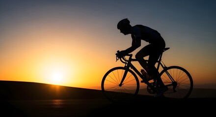 Fototapeta premium Silhouette of a cyclist on a road bike at sunset with a warm orange sky