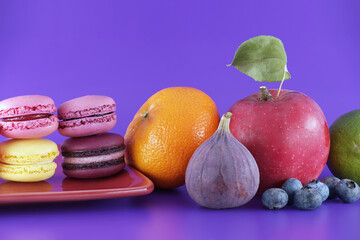 French macarons and fruits over purple background