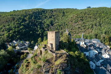 Naklejka premium Esch-sur-Sure, Wiltz, Grand-Duche de Luxembourg, September 07, 2025, Historic fortress panorama, Mountain stronghold overlooking trees, Castle perched above lush forest and flowing river