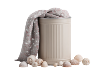 A beige metal container with fabric draped over it and seashells scattered around