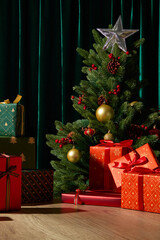 A beautifully lit Christmas tree with red and orange presents below. The dark green curtain and soft lights create an elegant seasonal mood. Blank space for design