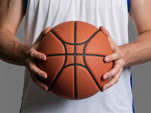 Focused basketball player gripping ball tightly in anticipation, ready for intense game action, training, or fitness challenge on the court - Powered by Adobe