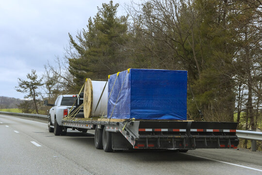 Truck hauls heavy equipment on flatbed trailer along American highway
