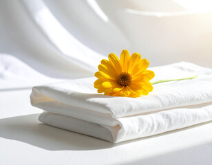 Tranquil Scene of White Fabric, Yellow Flower, and Fallen Petal in Sunlight.