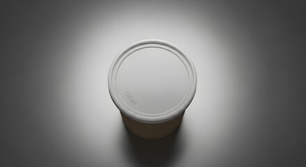 Top view of a white cylindrical container with lid under a spotlight on a gray surface