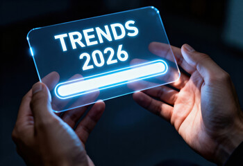 Hands holding a transparent screen displaying 'trends 2026' with a glowing loading bar, symbolizing future foresight