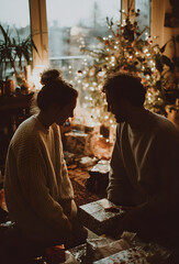 Fototapeta premium Romantic Couple Exchanging Christmas Gifts at Home – Cozy Holiday Lights