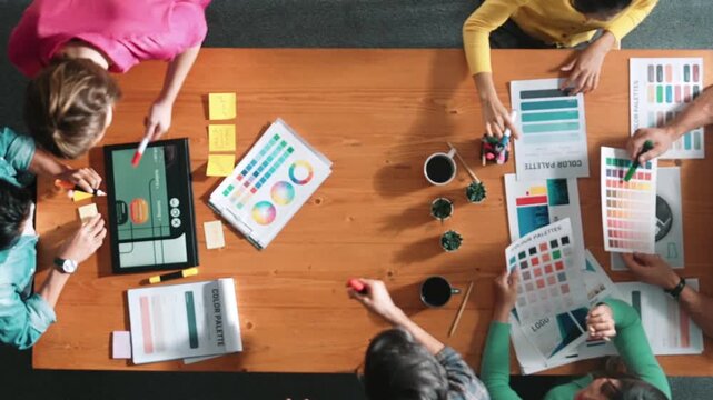 Top view of business people working together to design web design. Aerial view of designer brainstorming and discussing about website interface and looking at tablet with digital design. Symposium.
