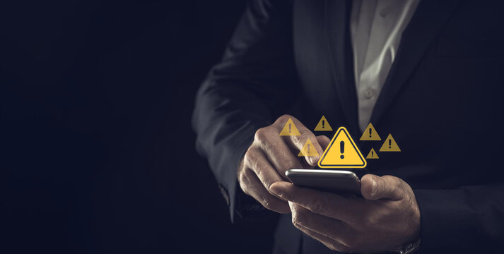 System hacked warning alert. Businessman use smartphone with warning sign for cyber attack. Ransomware, Virus, Spyware, Malware or Malicious software, Data breach, Cyber security and cybercrime.