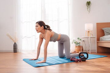 Woman stretching on yoga mat in a peaceful bedroom after workout, performing child pose. Healthy...