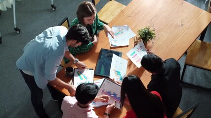 Top view of diverse group brainstorming marketing idea while looking at financial graph or stock market statistic chart report. Skilled business team share plan about start up project. Convocation. - Powered by Adobe