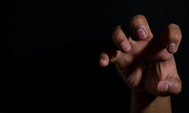 Curved hand gesture with extended fingers captured in moody lighting, showcasing expressive tension, reaction, or reaching movement on a dark background.
