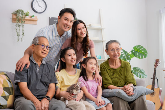 Asian family sitting together on the sofa in cozy living room at home. - Powered by Adobe