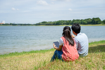 Rear view of young couple enjoy leisure time together outdoors in park.