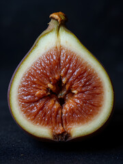 A halved fig revealing its juicy interior on a dark background