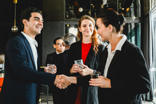 Business professionals greet each other with a handshake while networking at a corporate event, capturing a moment of connection, professionalism, and partnership in a formal setting.