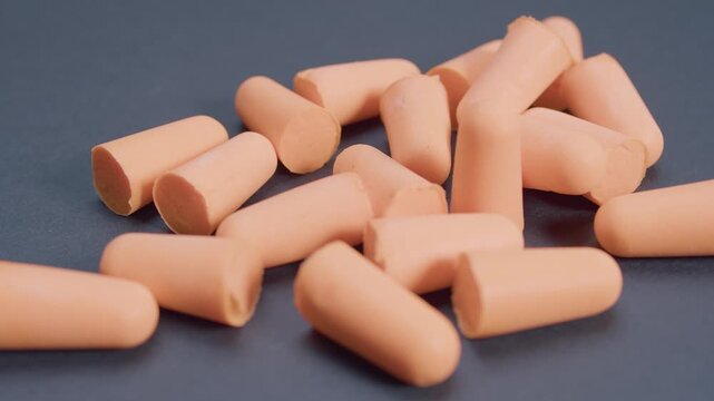 Orange ear plugs, hear protection on dark gray background, rotation view