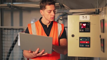 Focused engineer monitors industrial control panel. Precise operation and diligent analysis of data ensure system efficiency. Expertise displayed in technical environment.