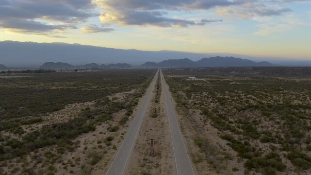 Av. la Mexicana, Chilecito, La Rioja, Argentina. Straight, endless highway across arid valley with mountains on horizon.