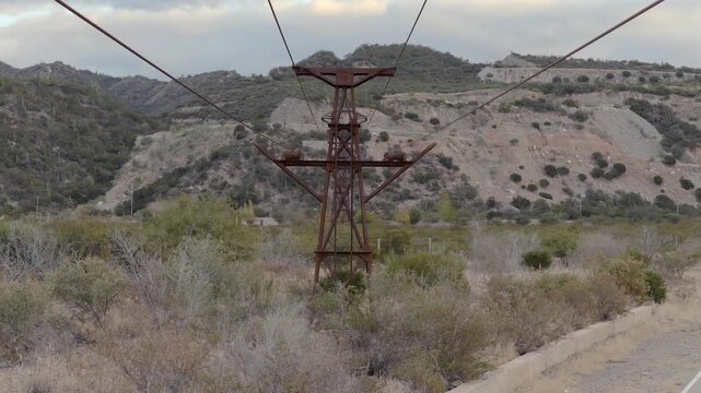 Historic mining cableway structure and wires extend through rugged landscape in La Mejicana. Cable Carril, Chilecito, La Rioja, Argentina.