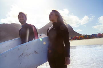 Couple, surfboard and smile at beach, vacation or outdoor for extreme sports, memory and bonding in summer. People, surfing equipment and swimwear with view, relationship or holiday with partner