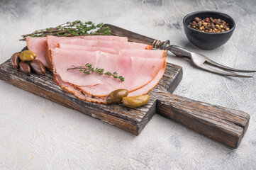 Spalla or lonza arranged neatly on aged wood with herbs and olives placed on a gray stone surface ideal for food stock compositions.