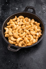 Closeup of cashews in a cast iron dish over a dark artistic background creating a bold natural scene ideal for gourmet and healthy eating visuals