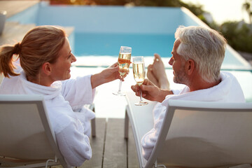 Deck chair, couple or toast by pool with champagne for vacation, peace or bonding at luxury resort. Cheers, mature people or outdoor with alcohol to relax, love and connection for holiday celebration