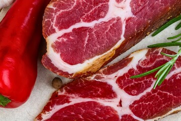 Close up of marbled raw meat with red pepper and rosemary
