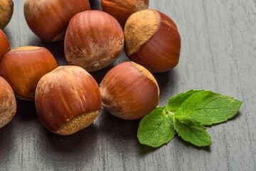 Close up of fresh hazelnuts with green mint leaves on a wooden surface