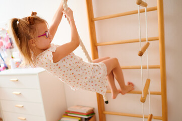 Young girl swinging on indoor climbing rope