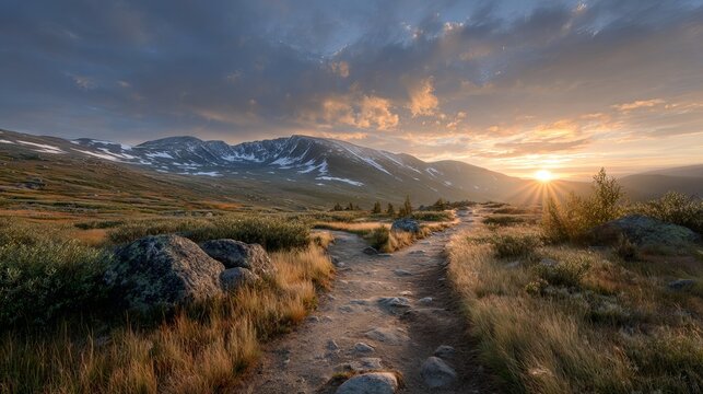 Sunset hiking trail across open tundra with rocky terrain and distant snow capped mountains scenic wilderness landscape background for travel adventure and nature concepts - Powered by Adobe