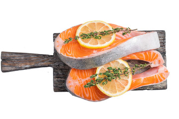 Raw salmon steak cuts topped with citrus slices and herbs on aged wood highlighting color texture and freshness ideal for food ads and recipes.