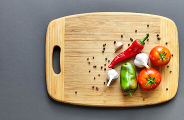 Composition of pepper, chili, garlic and tomato on a wooden surface.
