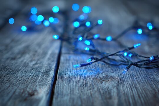 Cool-toned blue fairy lights on a natural wooden surface, warm ambience - Powered by Adobe
