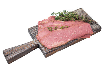 Thin pastrami slices on a distressed wooden board with fresh thyme, isolated on a white background. Smoked deli beef ready for cooking or serving.
