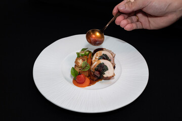 A chef delicately garnishing a beautifully plated gourmet meal, ready to be served. The dish features a medley of colorful ingredients on a textured plate
