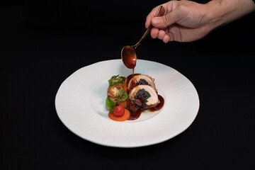 Gourmet dish being expertly drizzled with sauce on a pristine plate. The dish looks delicious and...