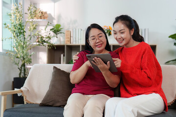 Digital Togetherness. Two women sharing a tablet experience in a bright living room.