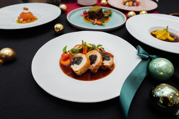 Gourmet dishes arranged on a festive holiday table with ornaments and a bow. The plates are elegantly arranged, showcasing culinary art